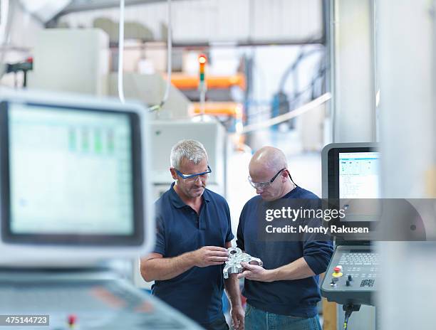 engineers inspecting complex metal component in factory - man and machine stock-fotos und bilder