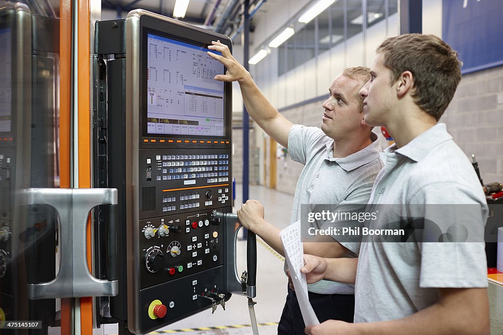 Workers looking at computer monitor in engineering factory