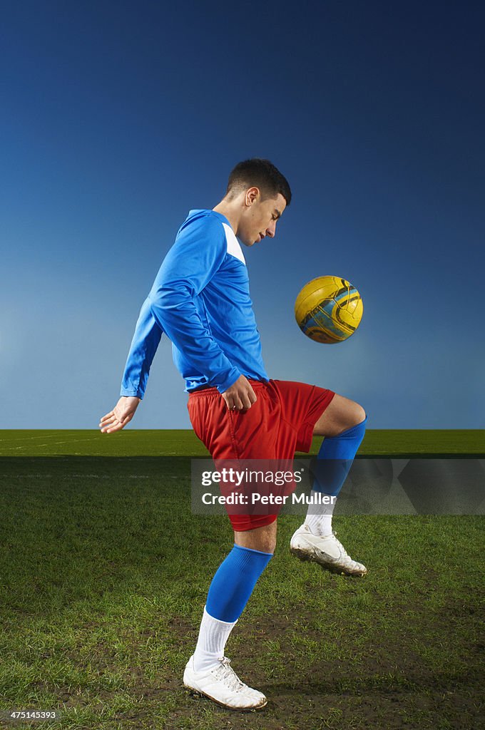 Young man playing keepy uppy with football