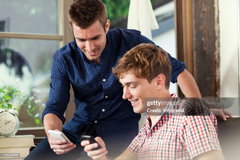 Two young men using smartphones