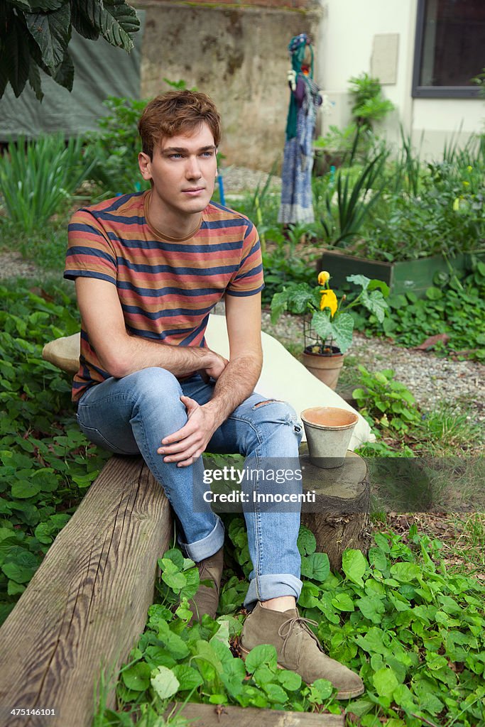 Young man sitting by vegetable garden