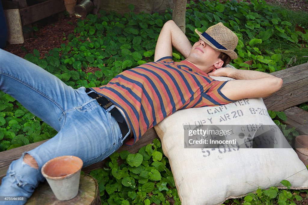 Young man wearing straw hat lying on sack