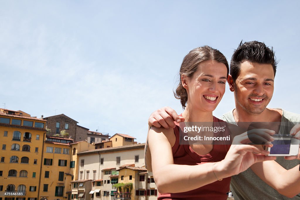 Man and woman photographing themselves on Ponte Vecchio, Florence, Tuscany, Italy