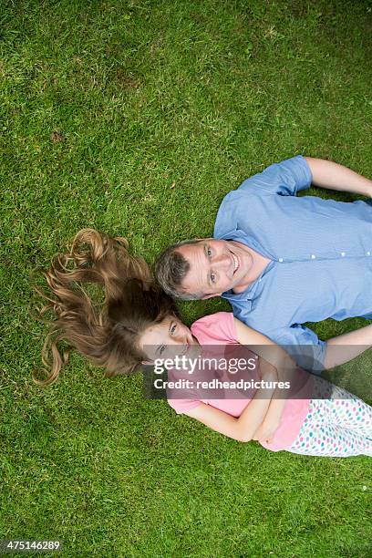 father and daughter lying on grass - happy tween girls lying on grass stock pictures, royalty-free photos & images