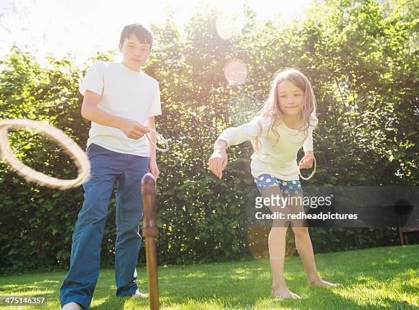 brother and sister playing hoopla in garden - ring toss imagens e fotografias de stock