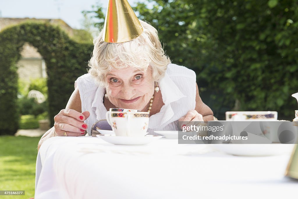 Senior woman wearing party hat looking at camera, smiling