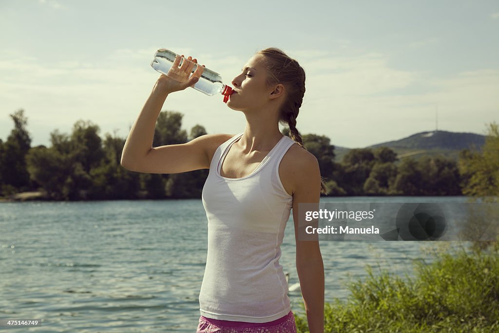 Young female jogger drinking bottled water