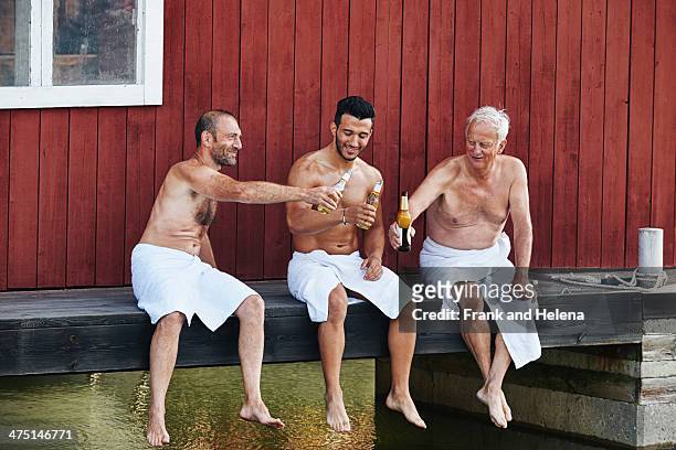 three men sharing a beer outside sauna - bierfles stockfoto's en -beelden
