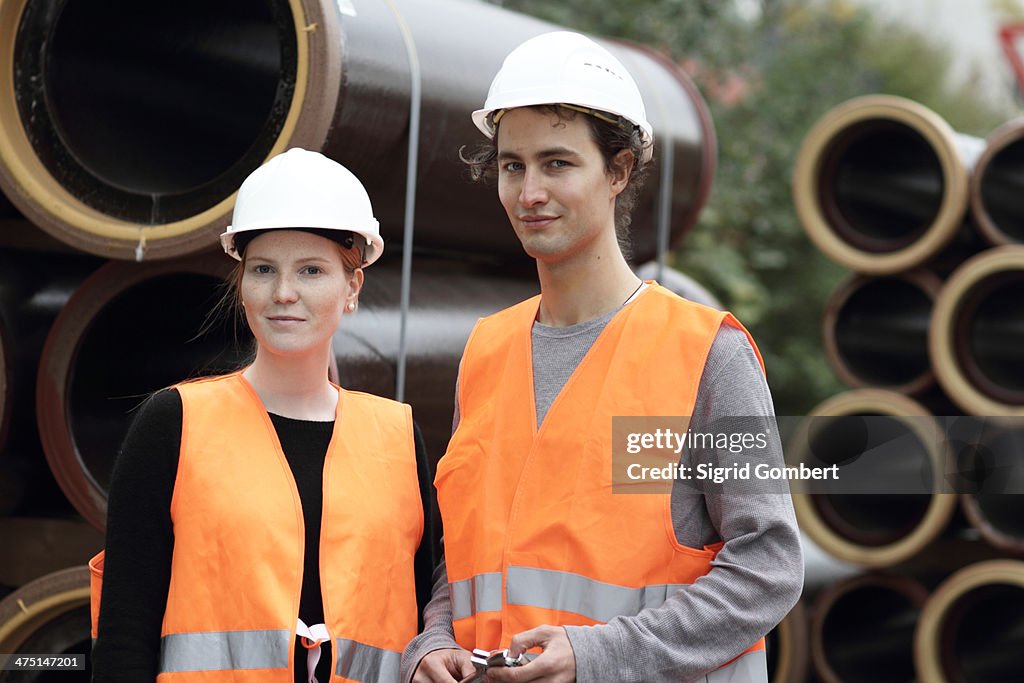 Construction workers standing in front of pipes
