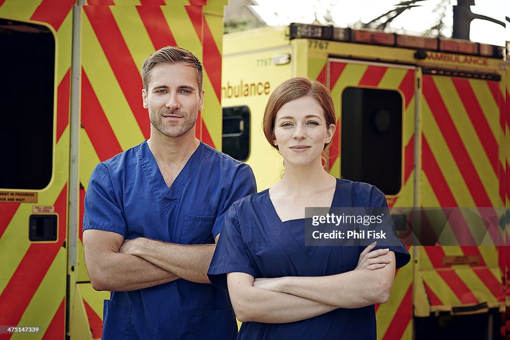 Portrait of two emergency medical technicians next to ambulance