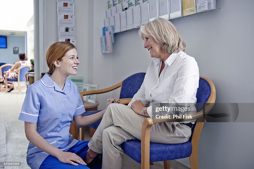 Female patient with nurse in hospital waiting room