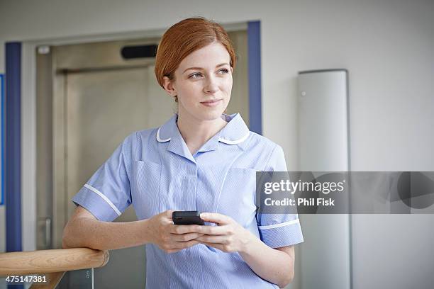 female nurse with mobile phone outside hospital lift - hospital elevator stock pictures, royalty-free photos & images
