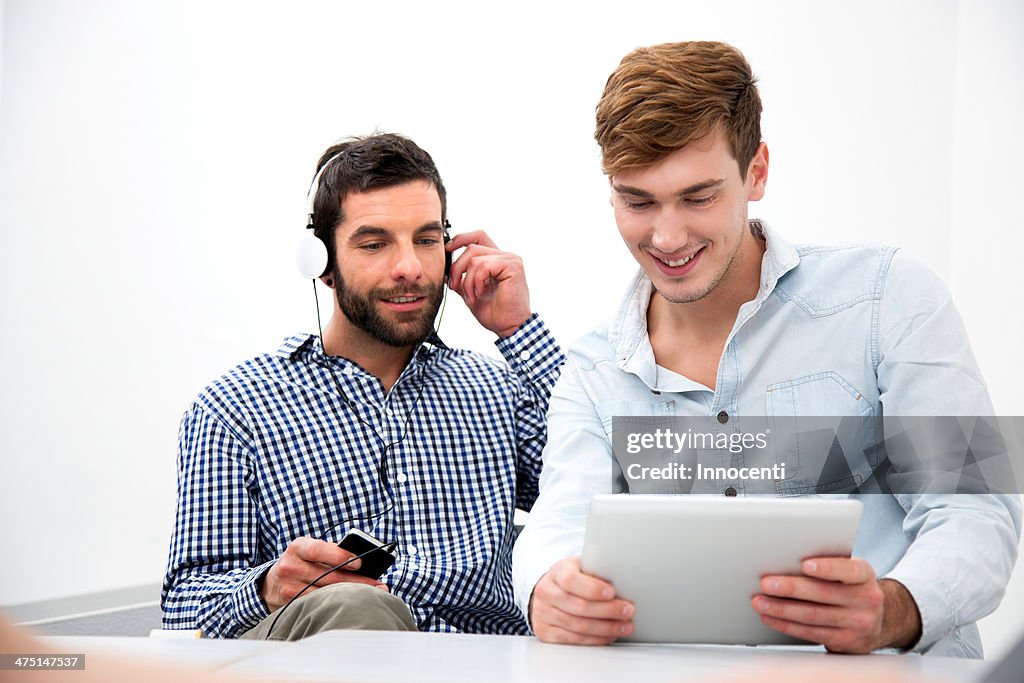 Two male colleagues using digital tablet