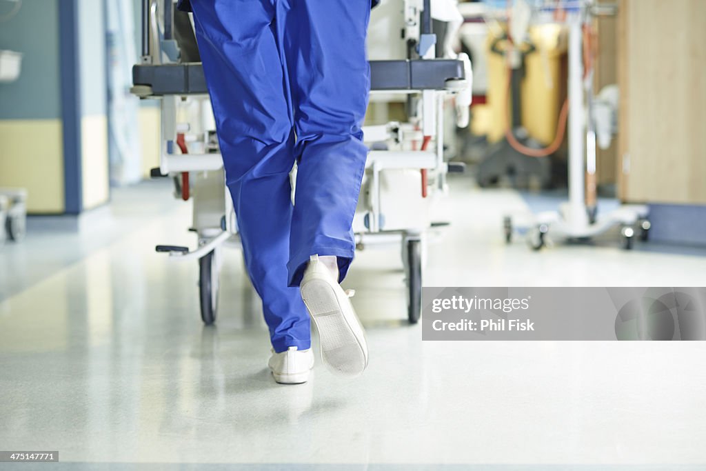 Legs of medic running with gurney along hospital corridor