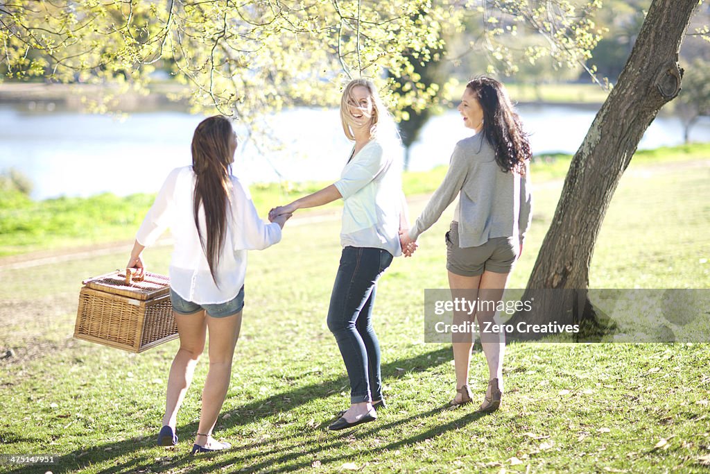 Three young women with picnic basket in park