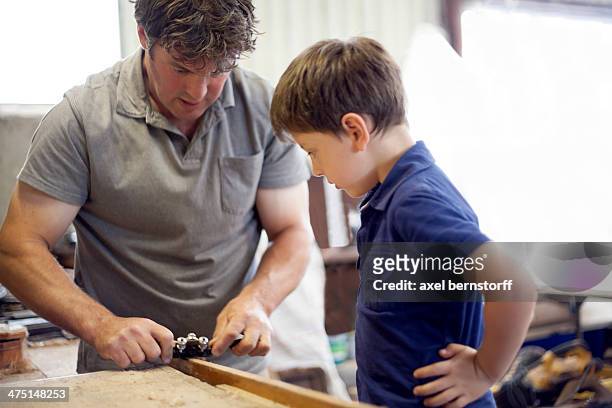 father showing son carpentry in boat  workshop - man reliable learning stockfoto's en -beelden