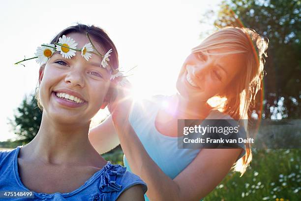 mother tying daisy chain around daughter's head - daisy chain stock pictures, royalty-free photos & images