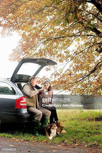 senior couple with dogs sharing coffee from car boot, norfolk, uk - norman elder stock-fotos und bilder