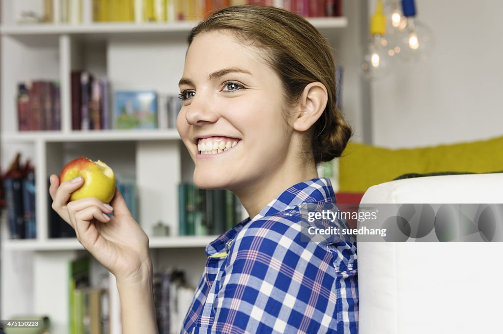 Young woman sitting on floor eating an apple