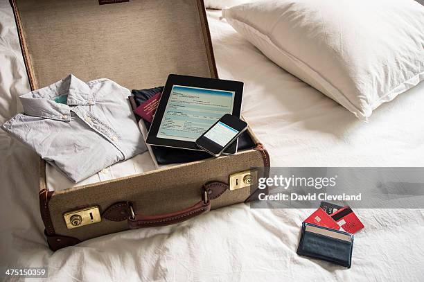 open suitcase on bed with digital tablet and mobile phone - oberteil stock-fotos und bilder