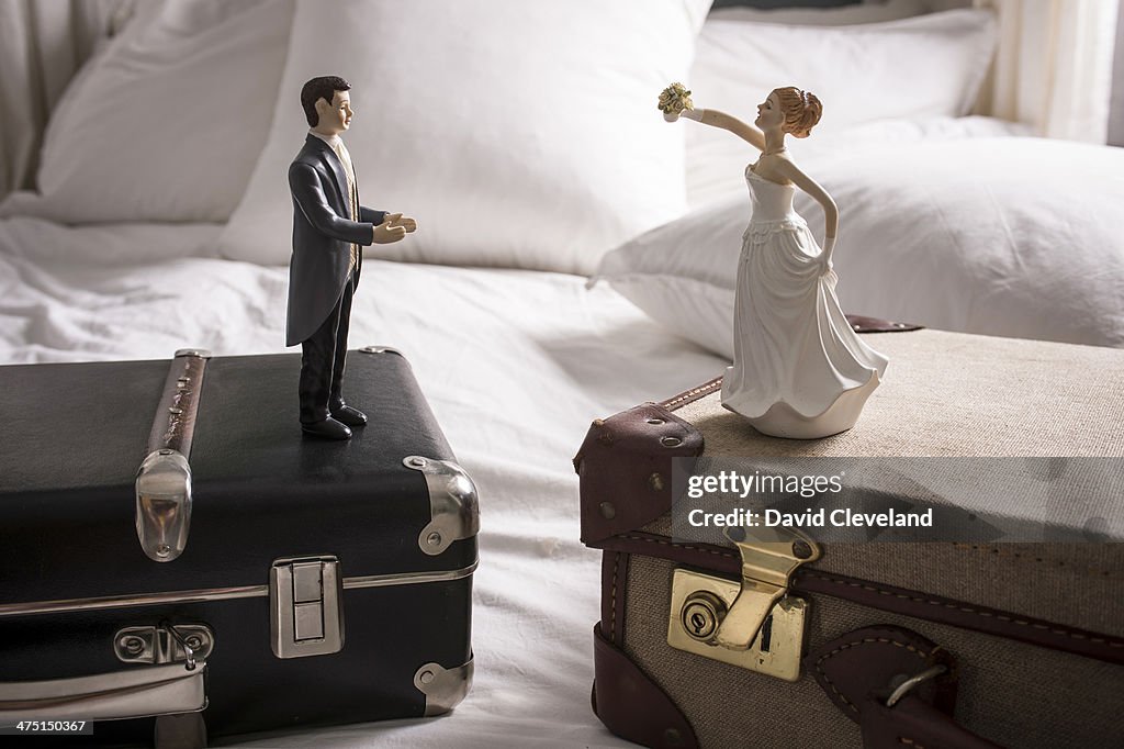 Wedding figurines on separate suitcases