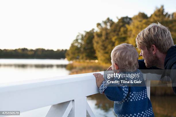 father and son looking at lake - autumn finland stock pictures, royalty-free photos & images