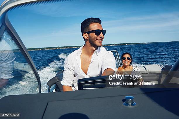 young man steering boat with woman in background, gavle, sweden - motor boats stock pictures, royalty-free photos & images