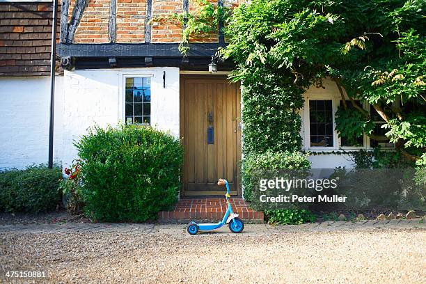 toy scooter parked outside cottage - surrey england stock pictures, royalty-free photos & images
