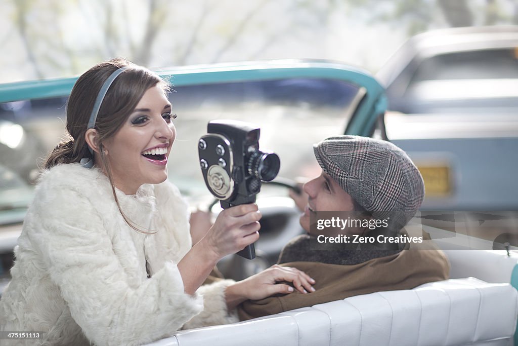 Woman in convertible with vintage hand-held video