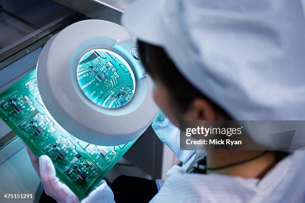 worker at small parts manufacturing factory in china looking through magnifier at microchips - computer chip stock pictures, royalty-free photos & images