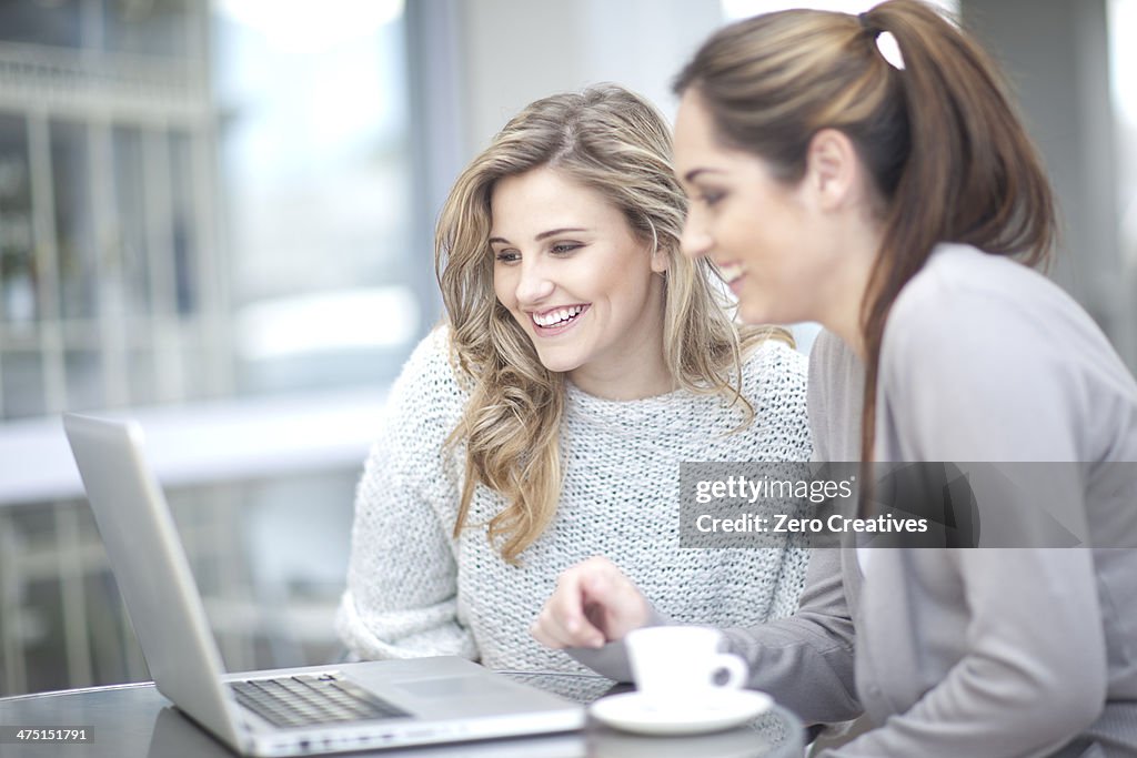 Young women at cafe with coffee, using laptop