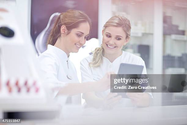 pharmacists having conversation, using digital tablet - 女性薬剤師 ストックフォトと画像