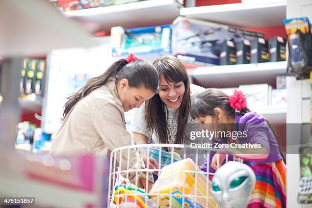 mother and two daughters choosing toys - woman picking up toys stock pictures, royalty-free photos & images