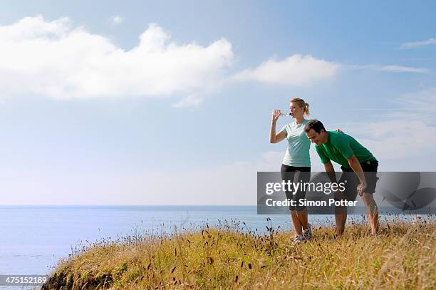 mid adult couple resting from exercise, thurlestone, devon, uk - vornüber beugen stock-fotos und bilder