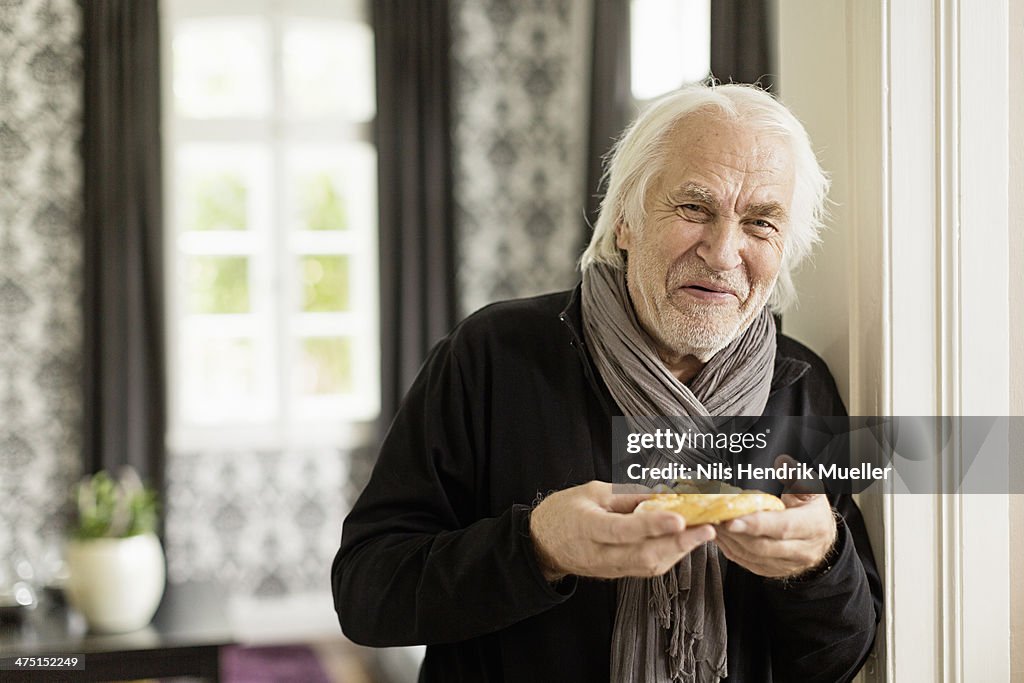 Senior man holding danish pastry