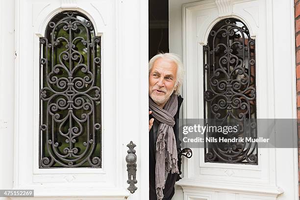 senior man peeking through doorway - mann haustür stock-fotos und bilder