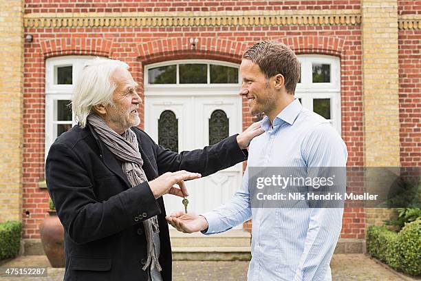 father giving son key outside house - erben stock-fotos und bilder