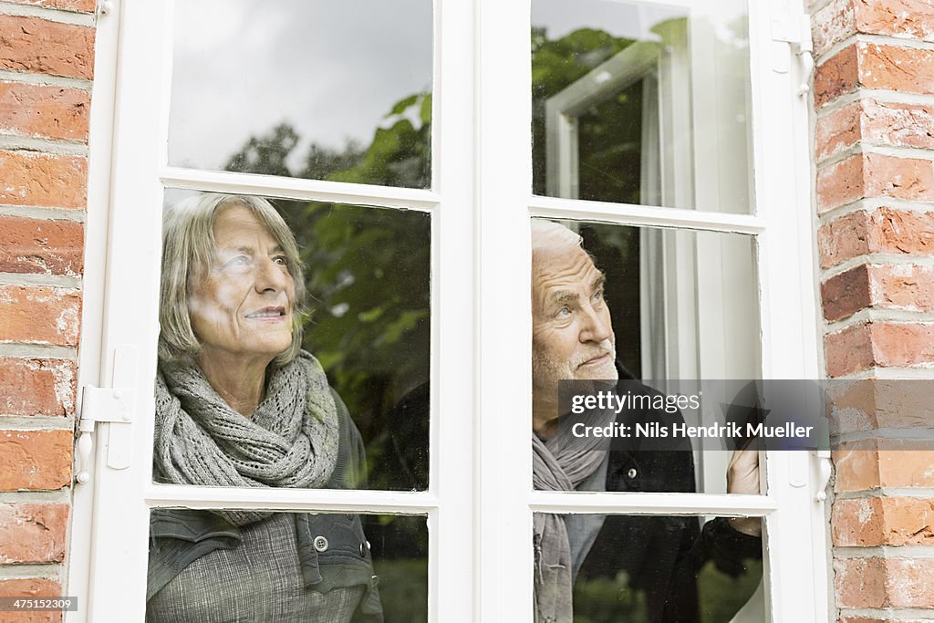 Senior couple looking through window