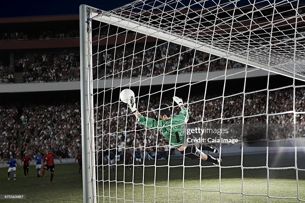 Goalie defending soccer net on field