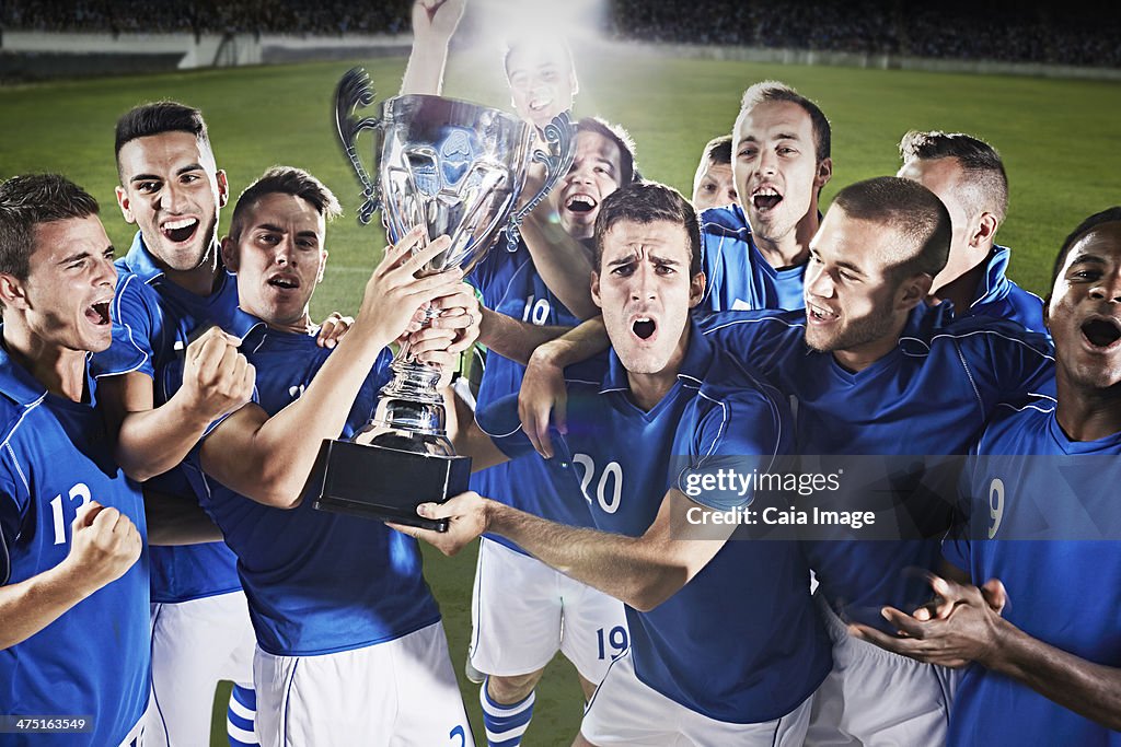 Soccer team cheering with trophy on field