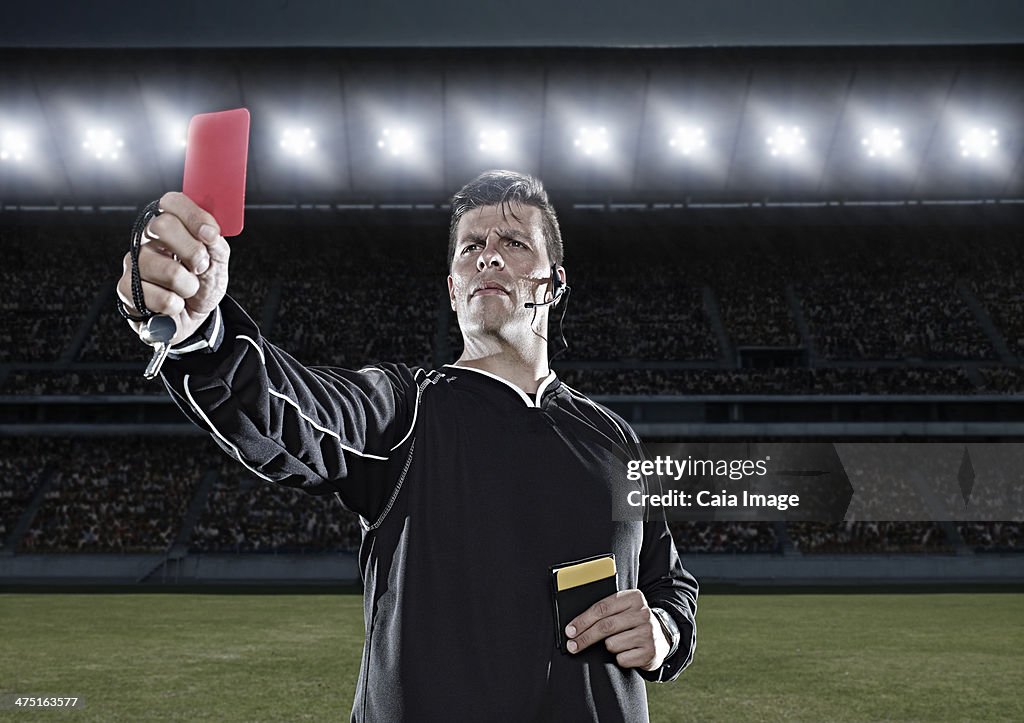 Referee flashing red card on soccer field