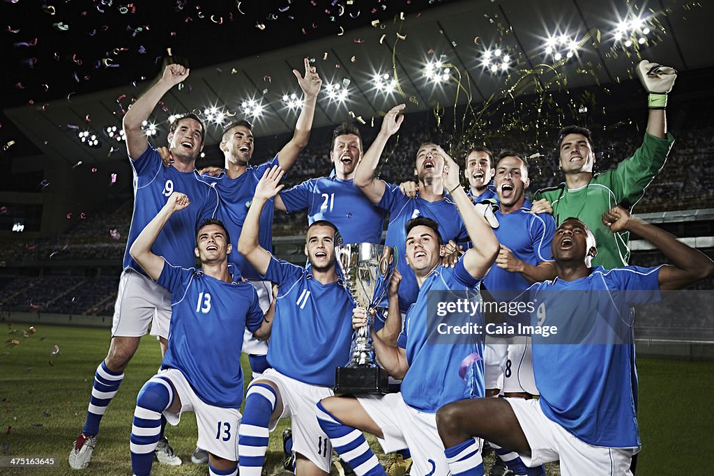 Soccer team cheering with trophy on field