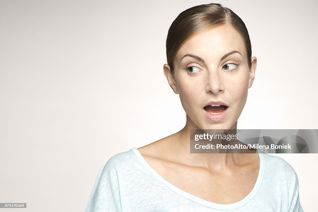 Young woman looking away with mouth open in surprise, portrait