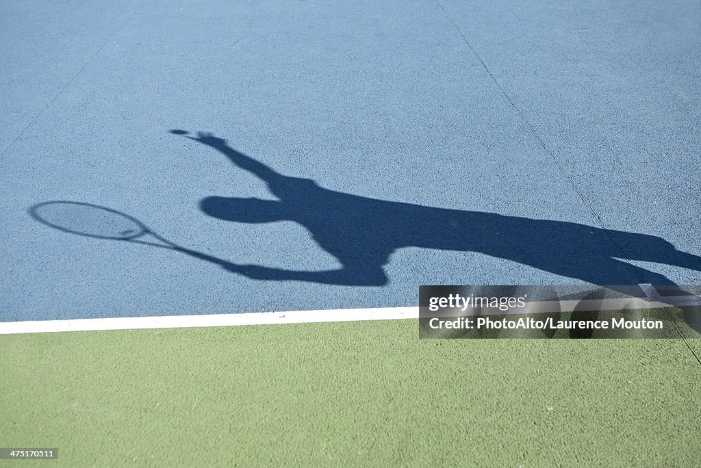 Shadow of tennis player serving ball