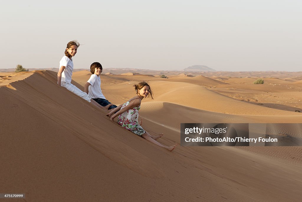 Children sitting on sand dune