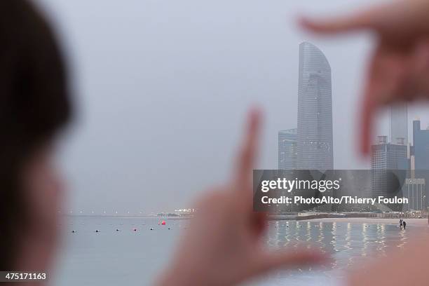 person looking through finger frame at coastal skyscraper - dubai frame stockfoto's en -beelden