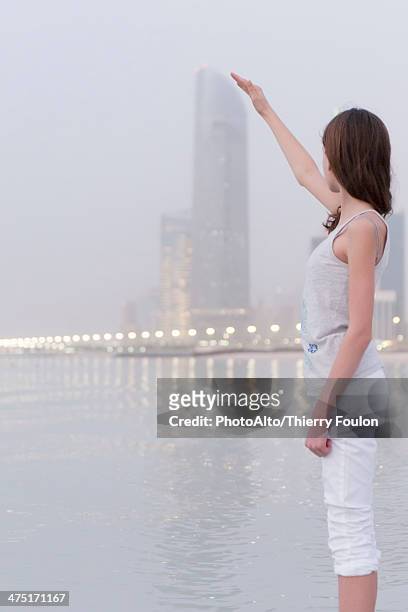 girl pretending to touch top of distant skyscraper - perspective artificielle photos et images de collection