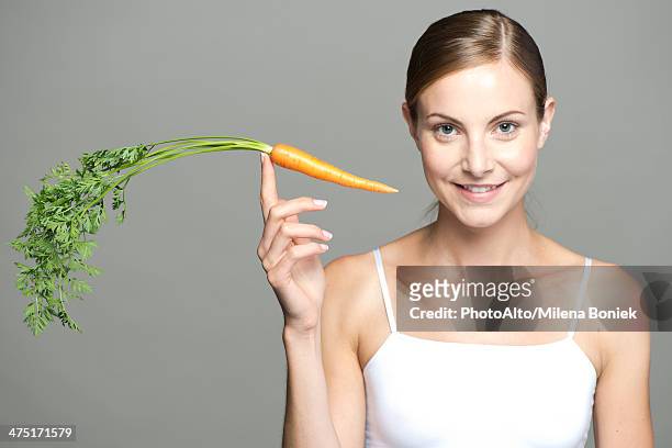 young woman balancing carrot on fingertip - human finger stock pictures, royalty-free photos & images