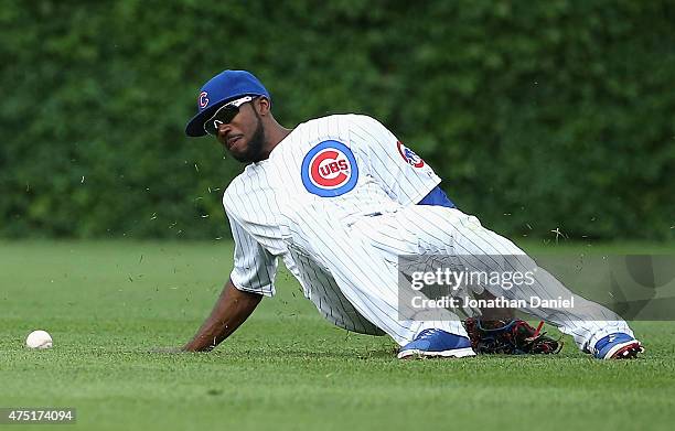 Dexter Fowler of the Chicago Cubs slips and falls trying to pick up a ball hit by Omar Infante of the Kansas City Royals in the 6th inning at Wrigley...