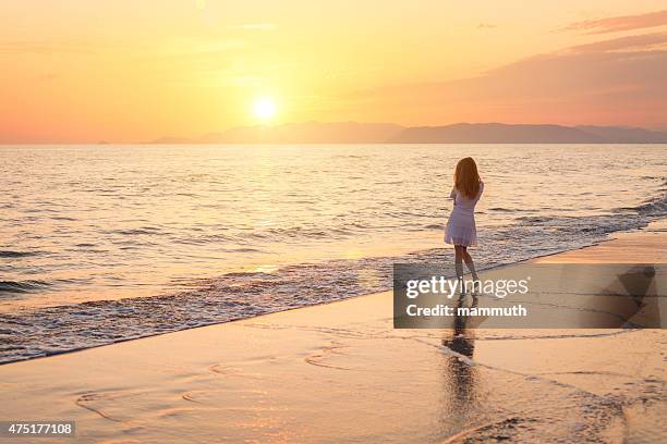 girl walking on the beach at sunset - brown hair waves stock pictures, royalty-free photos & images